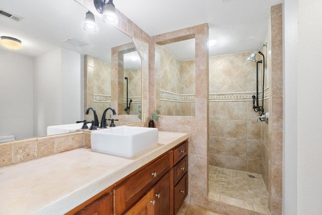Bathroom with visible vents, vanity, and a tile shower | Image 19