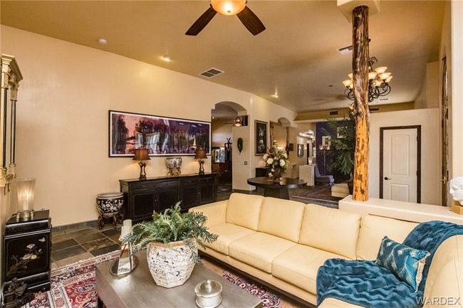 Living room featuring ceiling fan, arched walkways, and stone finish floors | Image 32