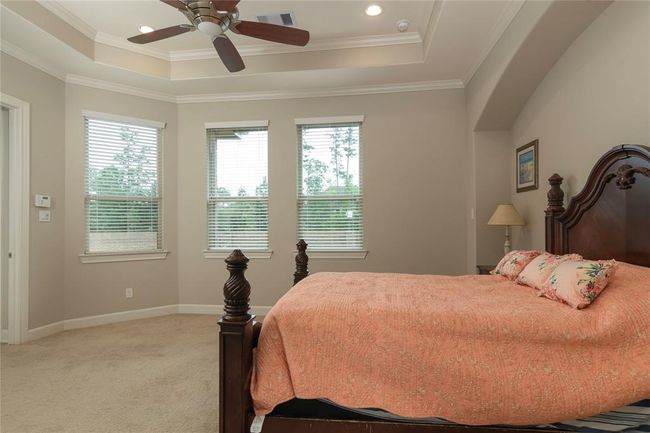 This bedroom features a tray ceiling with recessed lighting and a ceiling fan, large windows providing natural light, and a cozy space to fit all of your furniture needs. | Image 28