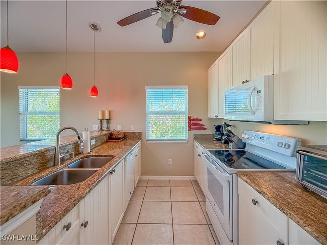 Kitchen featuring light tile patterned floors, white appliances, a sink, and a healthy amount of sunlight | Image 10