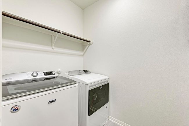 The washer and dryer convey in this tiled indoor utility room, with convenient shelving and hanging rod. | Image 37
