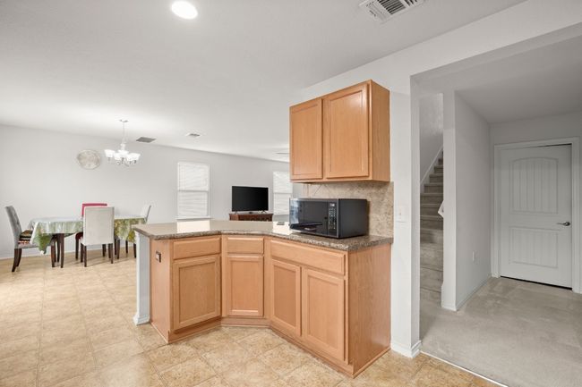Kitchen with black microwave, a chandelier, a peninsula, a desk, and pendant lighting | Image 8