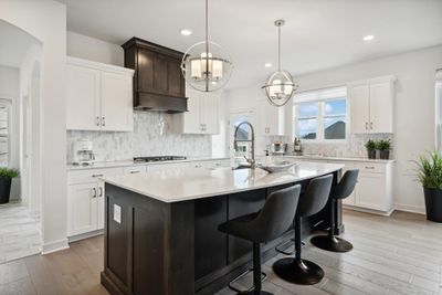 (Photo of model home, finishes will vary) This chef-ready kitchen is graced with a quartz center island ideal for casual dining and entertaining, complemented by extensive cabinetry room and high-end stainless steel appliances to inspire new recipes. | Image 1