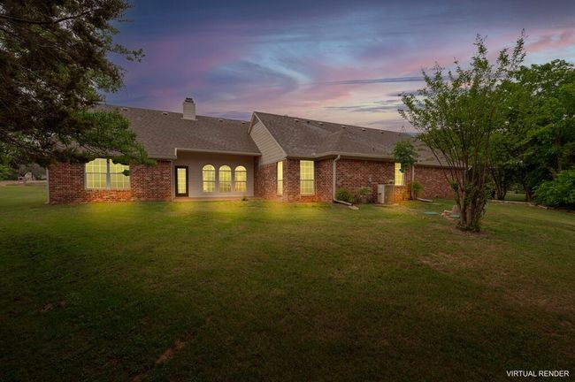 Back of house at dusk featuring a chimney, cooling unit, roof with shingles, a lawn, and brick siding | Image 29