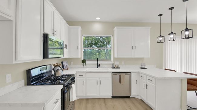 Kitchen with a sink, a peninsula, light wood-style flooring, appliances with stainless steel finishes, and white cabinetry | Image 5