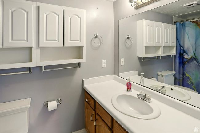 Full bathroom with toilet, vanity, and curtained shower | Image 14