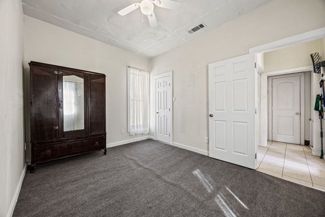 Unfurnished bedroom featuring visible vents, carpet flooring, ceiling fan, baseboards, and tile patterned floors | Image 18