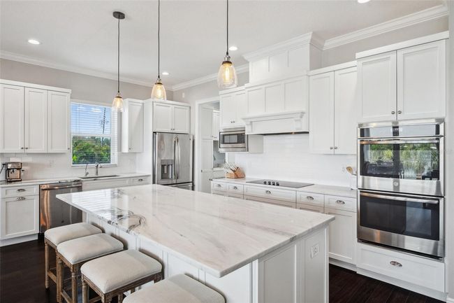 View of kitchen, with an oversized center island, double ovens, and custom DuraSupreme wood cabinetry. | Image 27