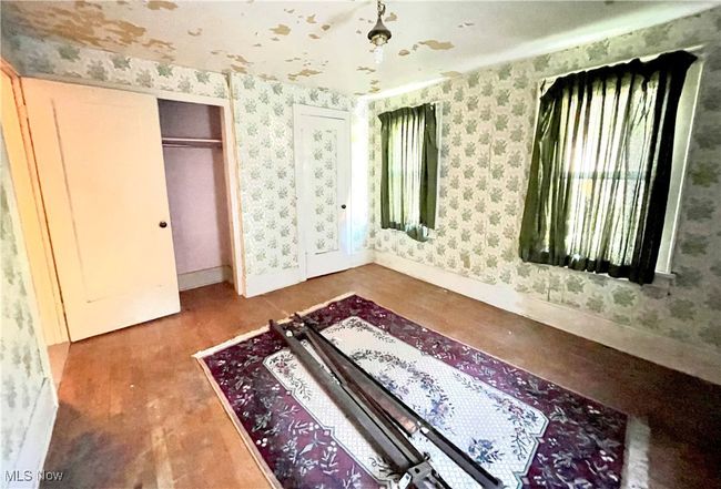 Unfurnished bedroom featuring baseboards, wallpapered walls, wood finished floors, and a closet | Image 11