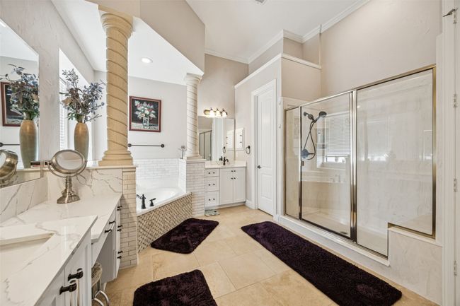 Bathroom with ornate columns, two vanities, a stall shower, a garden tub, and ornamental molding | Image 24