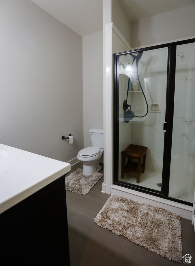 Bathroom with toilet, a shower stall, vanity, baseboards, and wood finished floors | Image 54