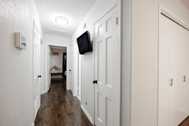 Corridor with a textured wall, dark wood-style floors, and attic access | Image 19
