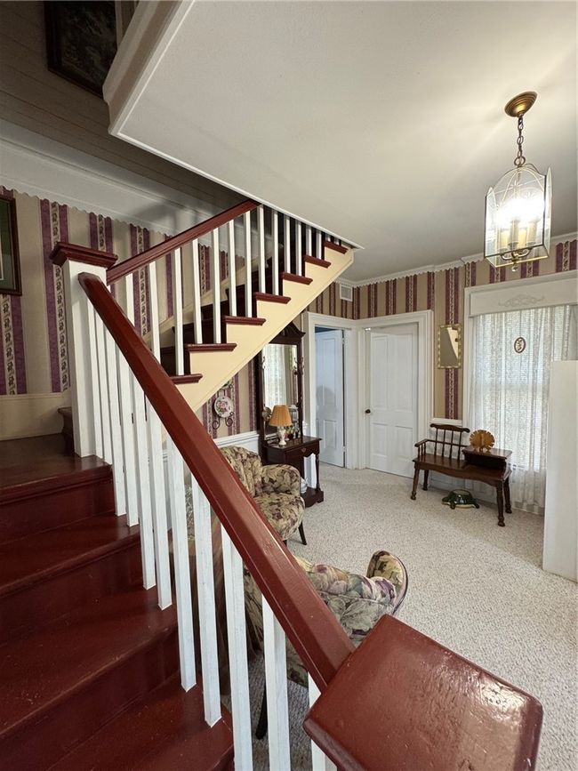 Staircase featuring wallpapered walls, carpet flooring, and a chandelier | Image 21