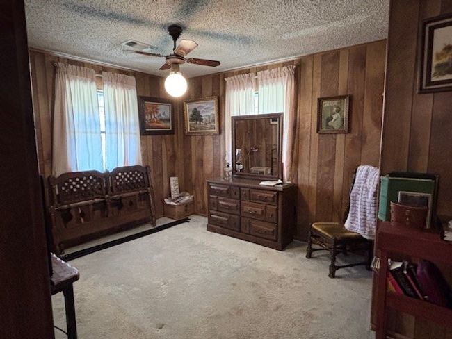 Sitting room with wooden walls, carpet, ceiling fan, and a textured ceiling | Image 19