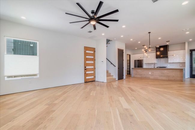 Unfurnished living room with light wood finished floors, recessed lighting, stairway, ceiling fan, and a chandelier | Image 6