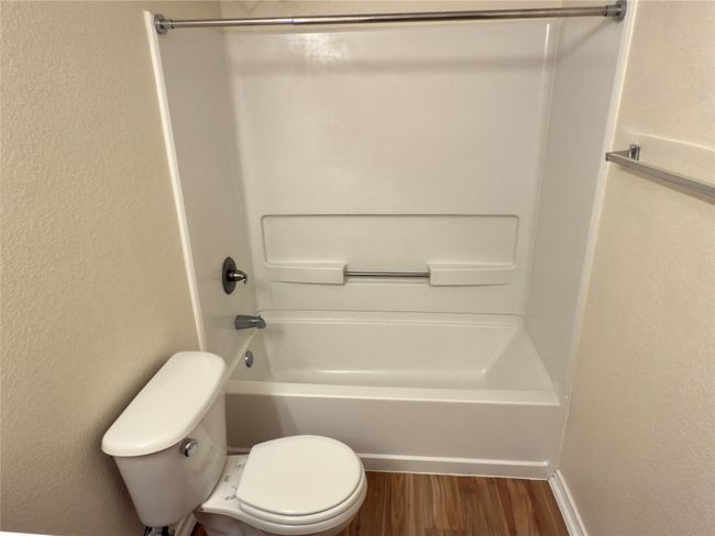 Full bath with wood finished floors, washtub / shower combination, and a textured wall | Image 34