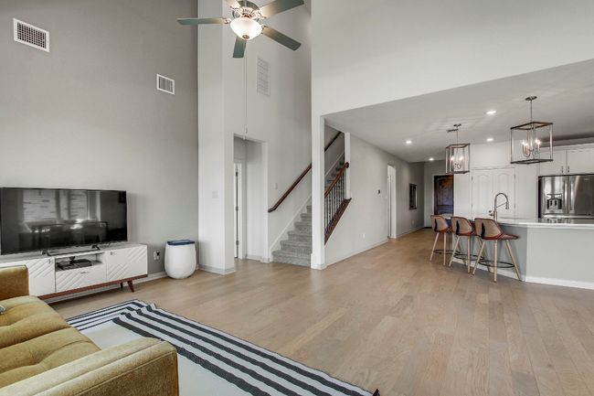 Living room with stairway, a towering ceiling, light wood-style floors, a ceiling fan, and recessed lighting | Image 14