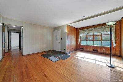 Living room with wood walls and light hardwood / wood-style floors | Image 3