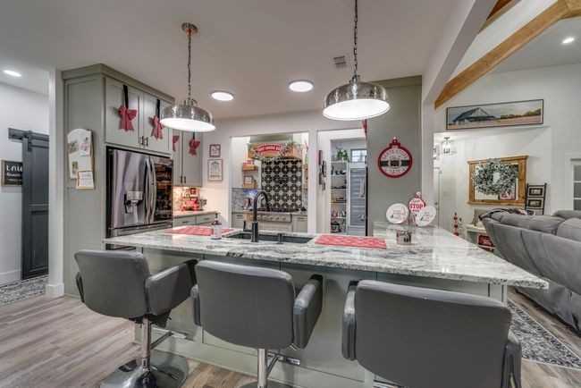 Kitchen featuring granite countertops, sink, hanging light fixtures, stainless steel refrigerator with ice dispenser, and light wood-type flooring | Image 8