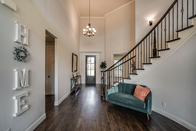 Entrance foyer with hardwood / wood-style floors, a notable chandelier, ornamental molding, and a high ceiling | Image 7