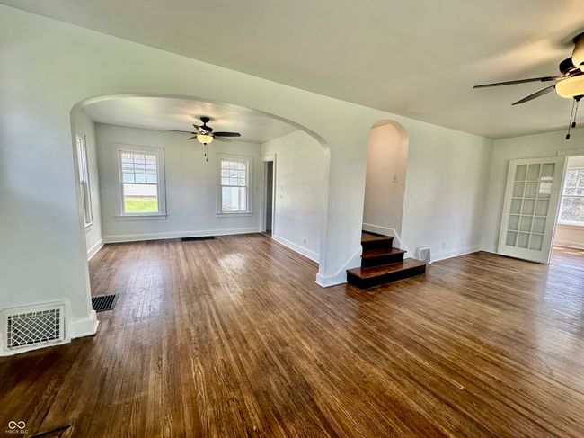 unfurnished living room with arched walkways, a ceiling fan, and visible vents | Image 21