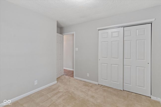 unfurnished bedroom with light carpet, a textured ceiling, and a closet | Image 11