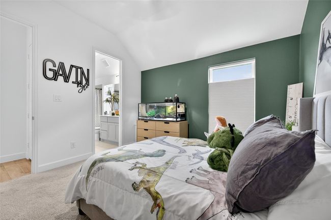 This bedroom features direct access to a full bathroom and offers an airy layout with elevated ceilings. A functional and inviting space ideal for guests or family members. | Image 16