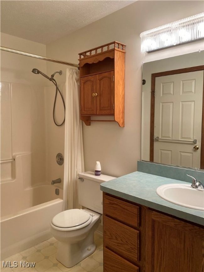 Bathroom featuring toilet, shower / bath combo, vanity, and a textured ceiling | Image 21