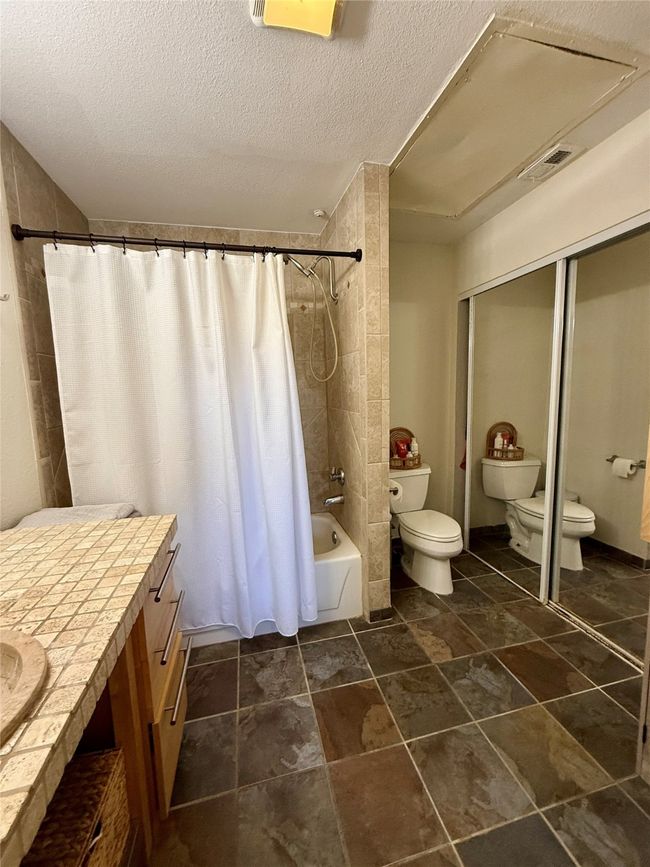 Bathroom with shower / tub combo with curtain, visible vents, toilet, a textured ceiling, and vanity | Image 29