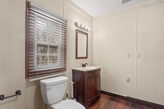 Bathroom featuring wood-type flooring, toilet, tile walls, vanity, and ornamental molding | Image 19