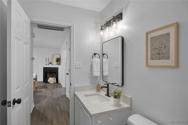 Half bath with vanity, a fireplace with flush hearth, toilet, and wood finished floors | Image 21