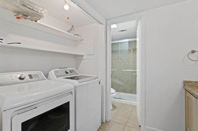 Downstairs utility room with granite counters, built in shelving and washer/dryer. | Image 14