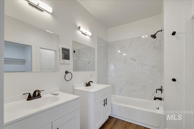Full bath featuring two vanities, shower / washtub combination, wood finished floors, and heating unit | Image 19