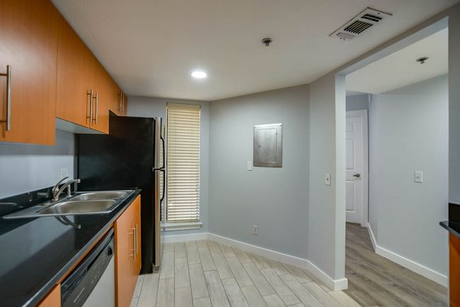 Kitchen with dishwashing machine, light wood finished floors, dark countertops, brown cabinetry, and recessed lighting | Image 6