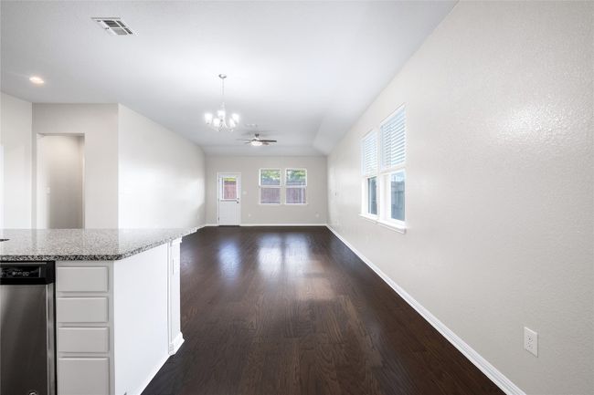 Unfurnished living room with a chandelier, dark wood-style floors, and a ceiling fan | Image 11