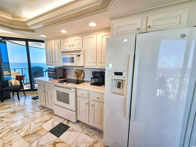 Kitchen featuring crown molding, light countertops, a tray ceiling, recessed lighting, and white appliances | Image 12
