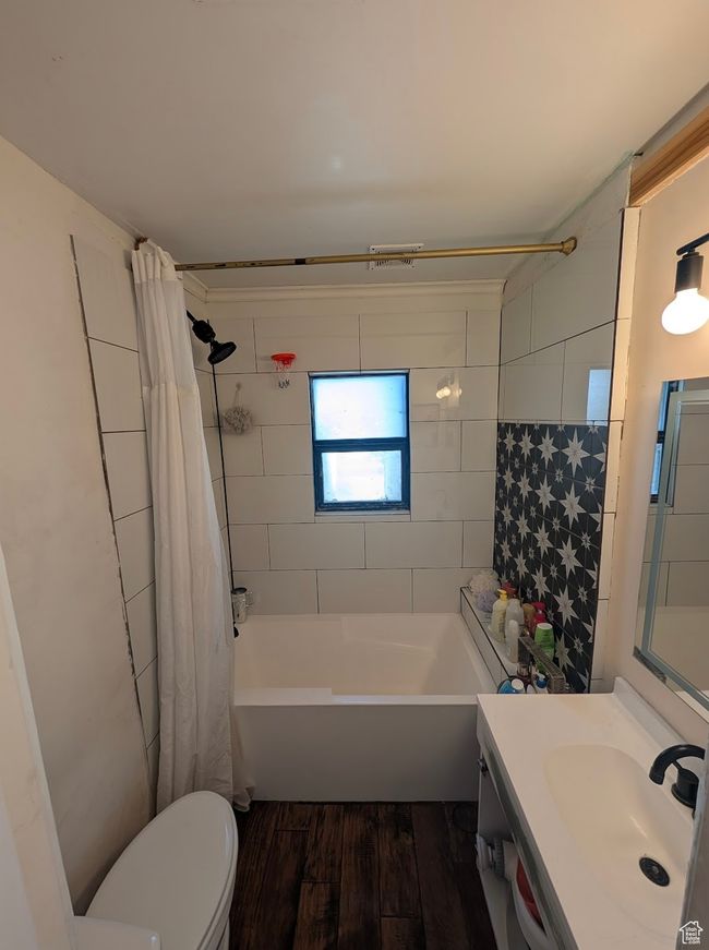 Full bathroom featuring shower / bathtub combination with curtain, vanity, toilet, and wood finished floors | Image 4