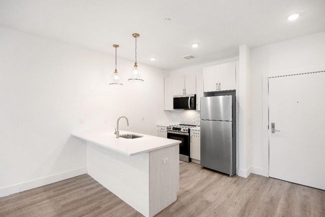 Kitchen with appliances with stainless steel finishes, a sink, a peninsula, light wood-style flooring, and recessed lighting | Image 31