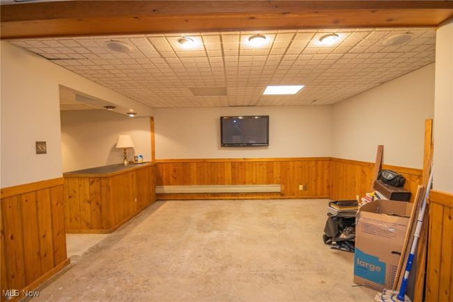 Finished below grade area featuring wainscoting, wooden walls, and a baseboard radiator | Image 11