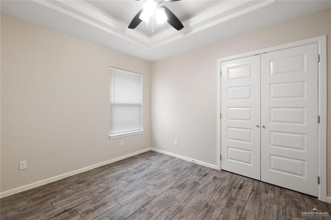 Unfurnished bedroom featuring a raised ceiling, wood finished floors, a closet, and ceiling fan | Image 8