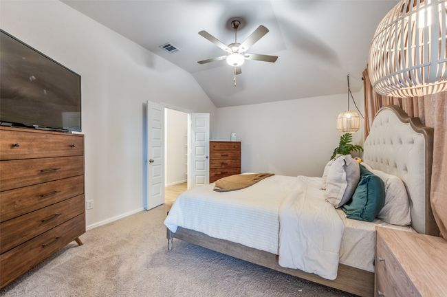 Bedroom with baseboards, vaulted ceiling, a ceiling fan, visible vents, and light colored carpet | Image 14