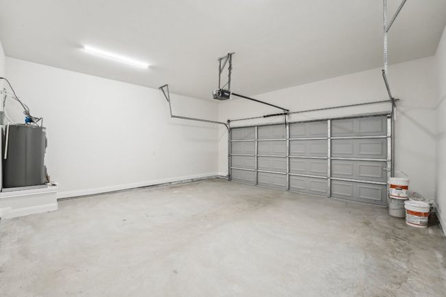 Garage featuring electric water heater and a garage door opener | Image 35