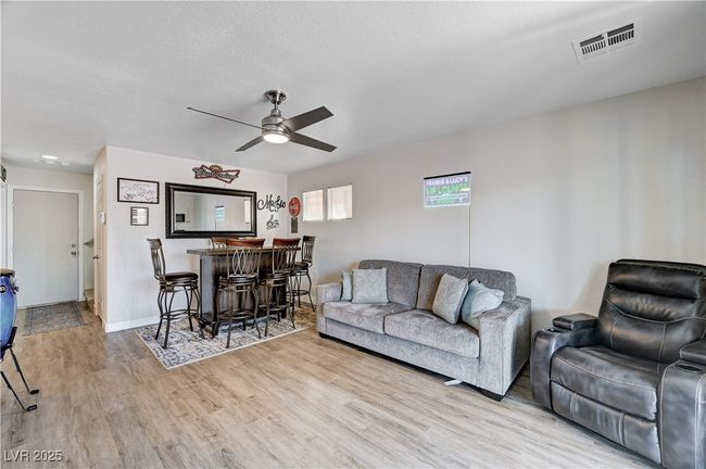 Living room with ceiling fan, wood finished floors, and a bar | Image 21