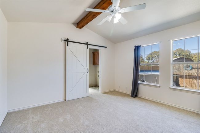Unfurnished room with baseboards, ceiling fan, light colored carpet, lofted ceiling with beams, and a barn door | Image 22