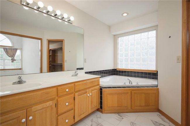 Full bath featuring double vanity, healthy amount of natural light, a bath, and marble finish flooring | Image 19