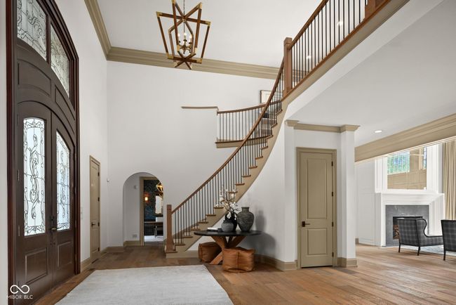 foyer entrance featuring stairway, a towering ceiling, arched walkways, wood finished floors, and a high end fireplace | Image 6