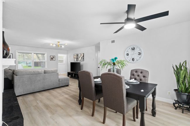 Dining area featuring light wood finished floors, baseboards, visible vents, ceiling fan, and a fireplace | Image 11