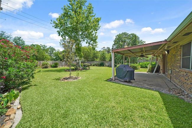 Pictured from the side of the home is shown more of the large, well maintained backyard. This spacious backyard offers endless possibilities, creating a serene outdoor space. A covered patio provides an ideal spot for relaxation and entertaining. | Image 29