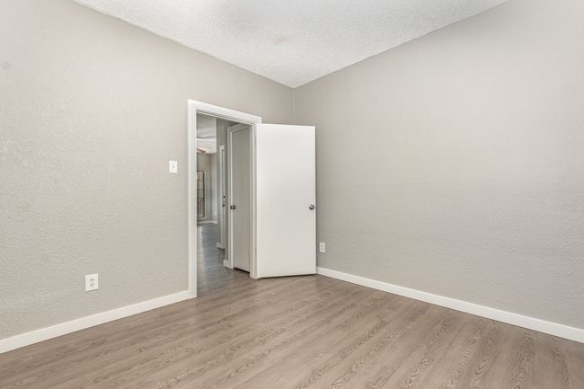 Empty room with light wood-type flooring, baseboards, a textured ceiling, and a textured wall | Image 19