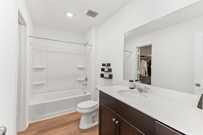 Bathroom featuring vanity, wood finished floors, shower / washtub combination, and a walk in closet | Image 24